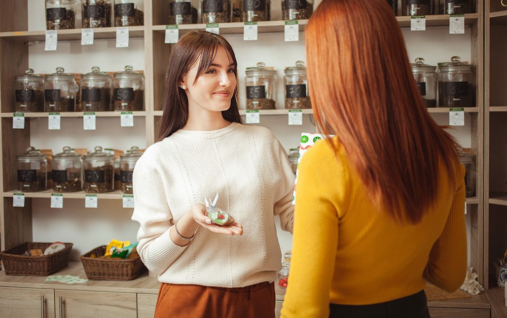 Funcionária de uma loja de produtos naturais colocando em prática algumas dicas de educação alimentar para dar informações a sua cliente.